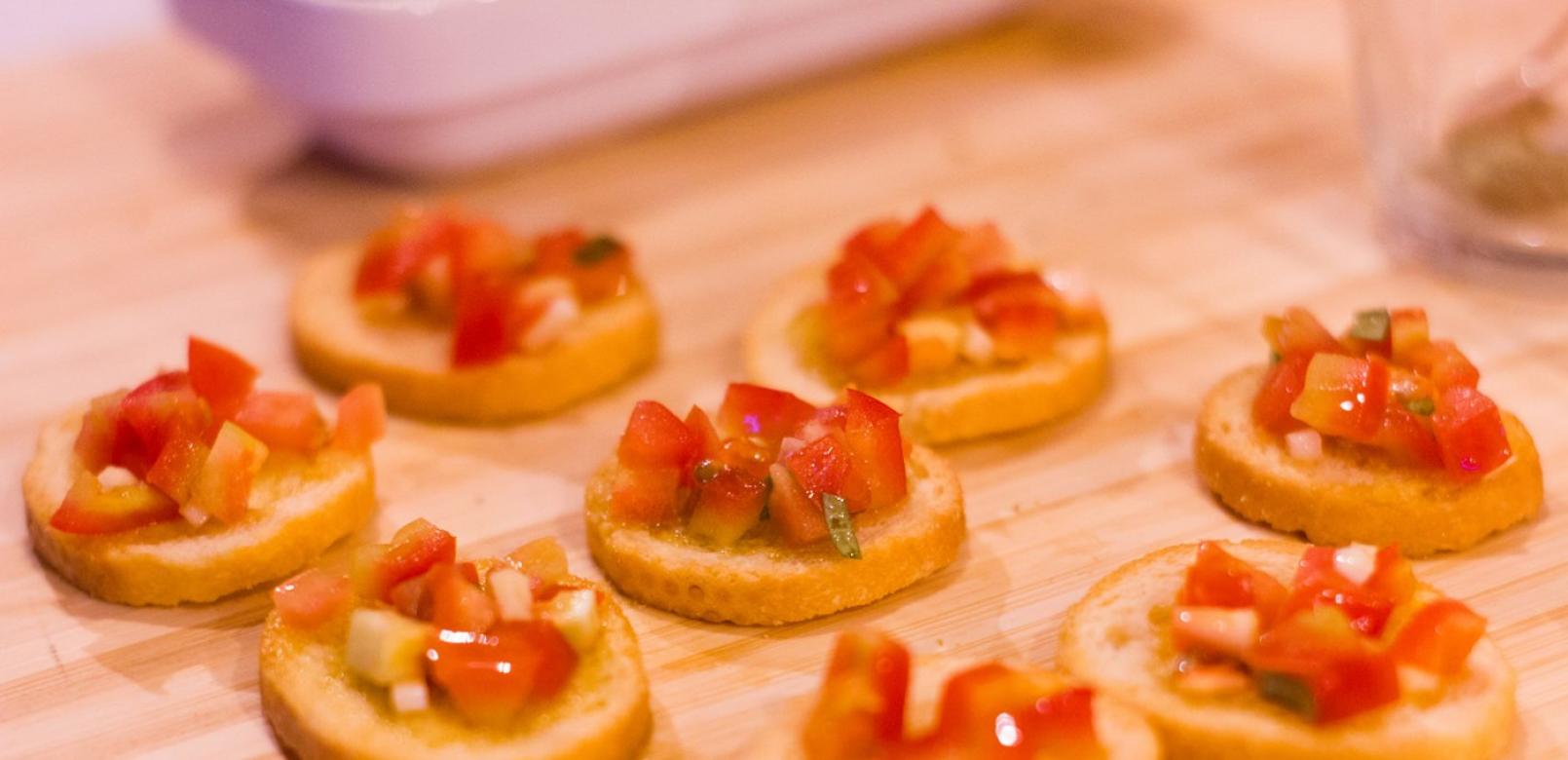 Bruschette con pomodori a dadini su crostini di pane su tagliere di legno.