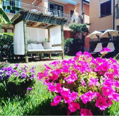 Giardino fiorito con seduta coperta e dondolo in un cortile soleggiato.