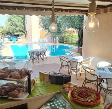 Colazione all'aperto con vista piscina, dolci e croissant su tavolo apparecchiato.