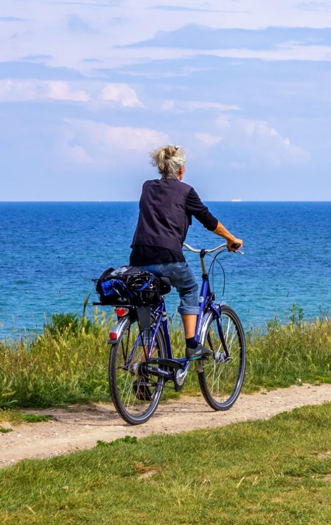 Persona in bicicletta su un sentiero costiero, con vista sull'oceano.