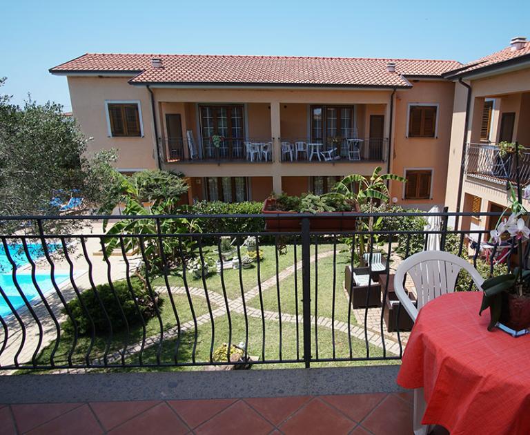 Vista su cortile con giardino, piscina e tavolo con orchidea.