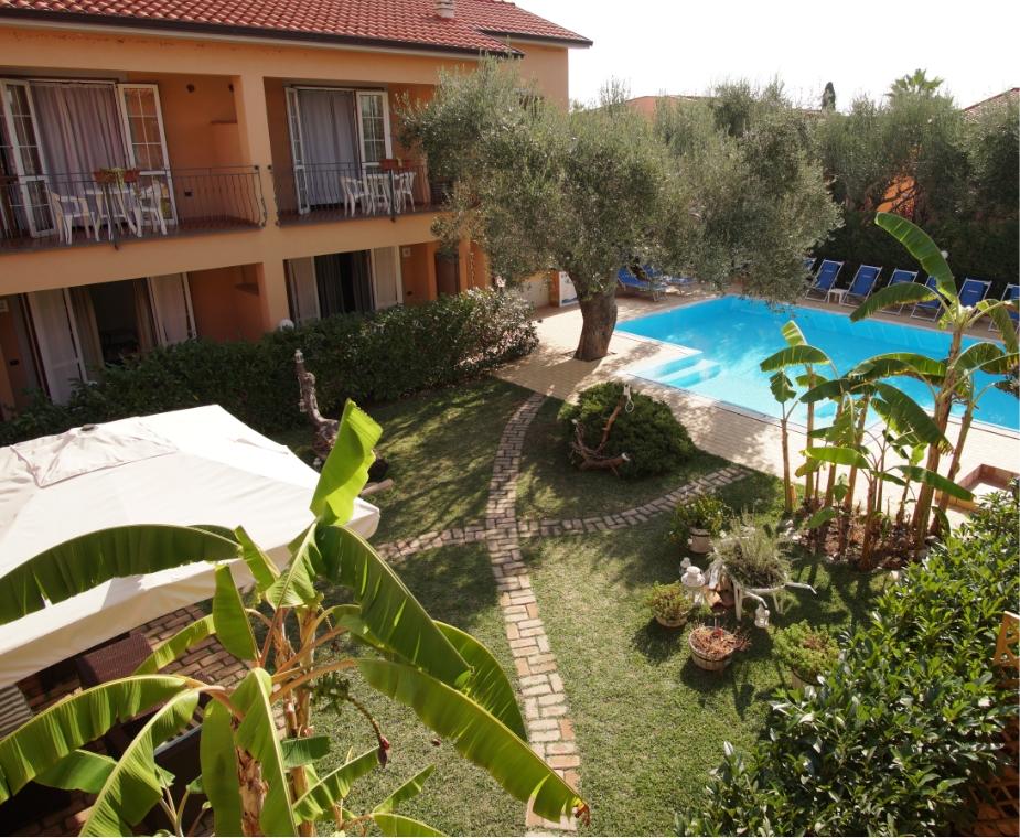 Giardino con piscina, piante tropicali e edificio a due piani.